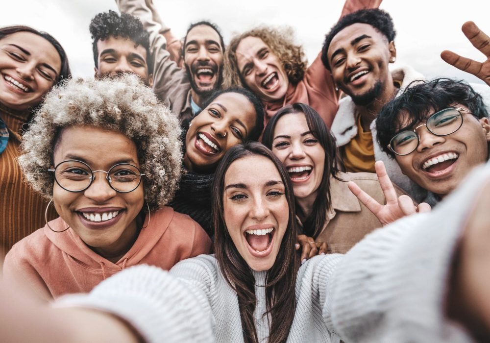 Multicultural community of young people smiling together at came